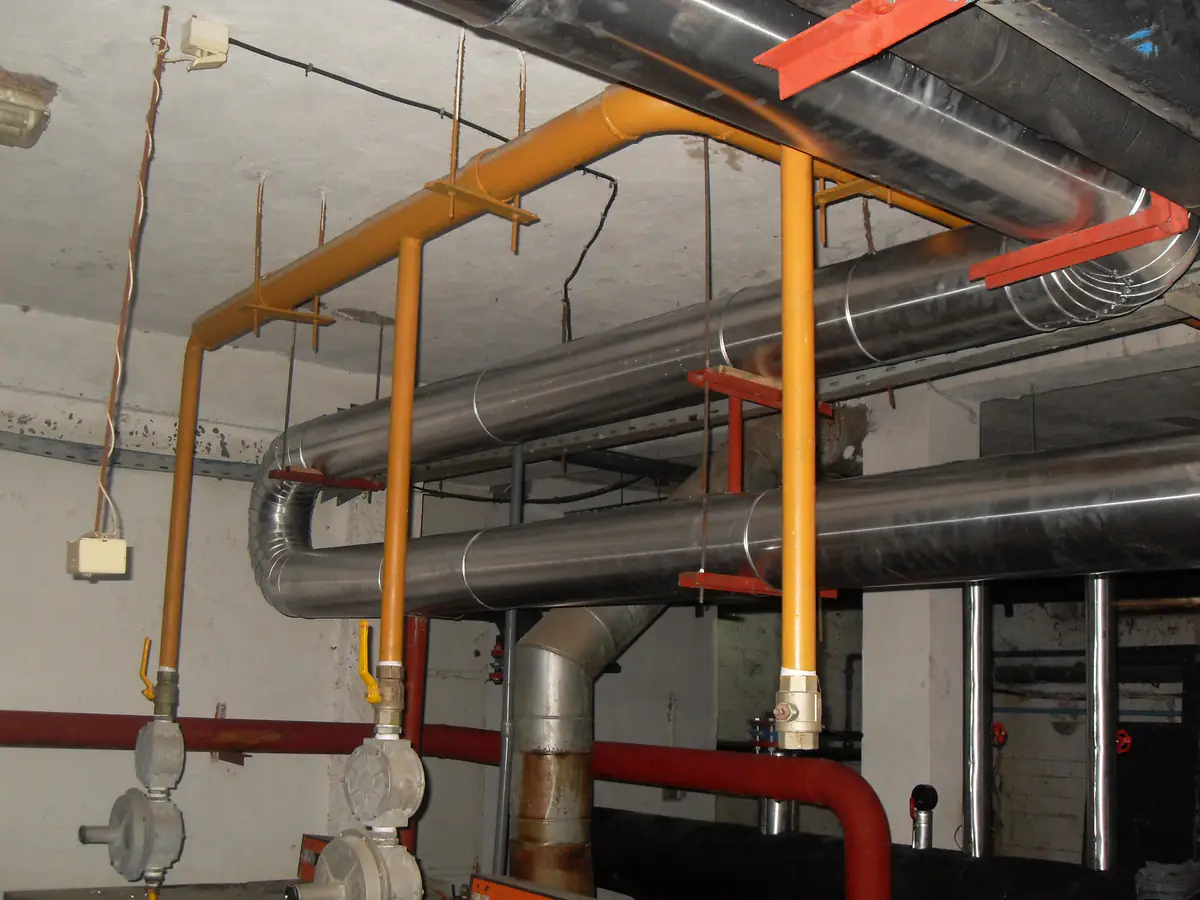 Réseaux d'eau chaude calorifugés et alimentation gaz repérée en jaune dans une chaufferie industrielle