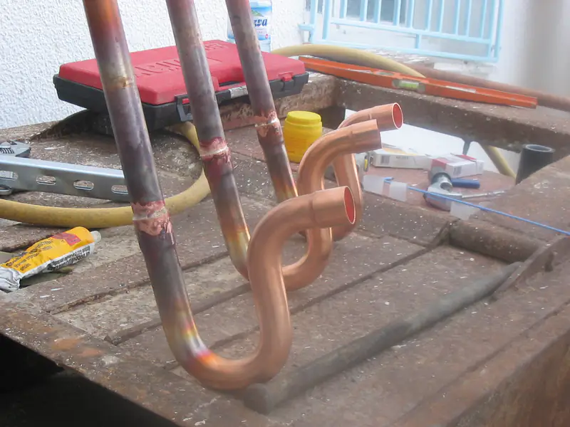 Coudes en cuivre brasés posés sur l'établi du chantier