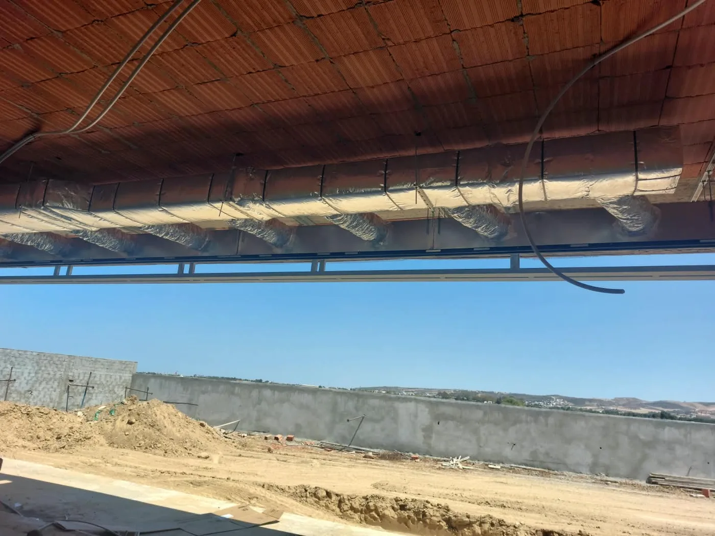 Gaines de climatisation isolées, suspendues sous la dalle avant la fermeture des faux plafonds