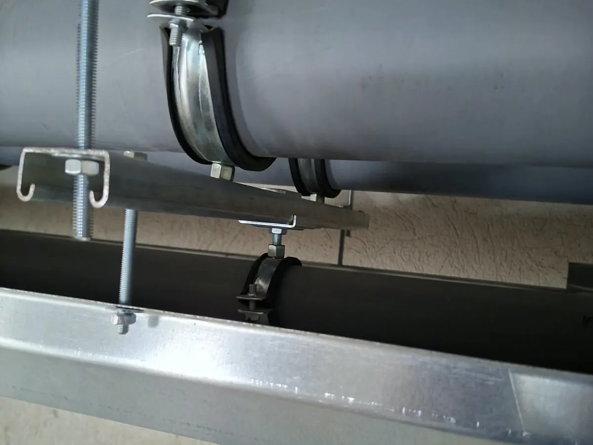 Collier de fixation serrant une canalisation sur son rail de support