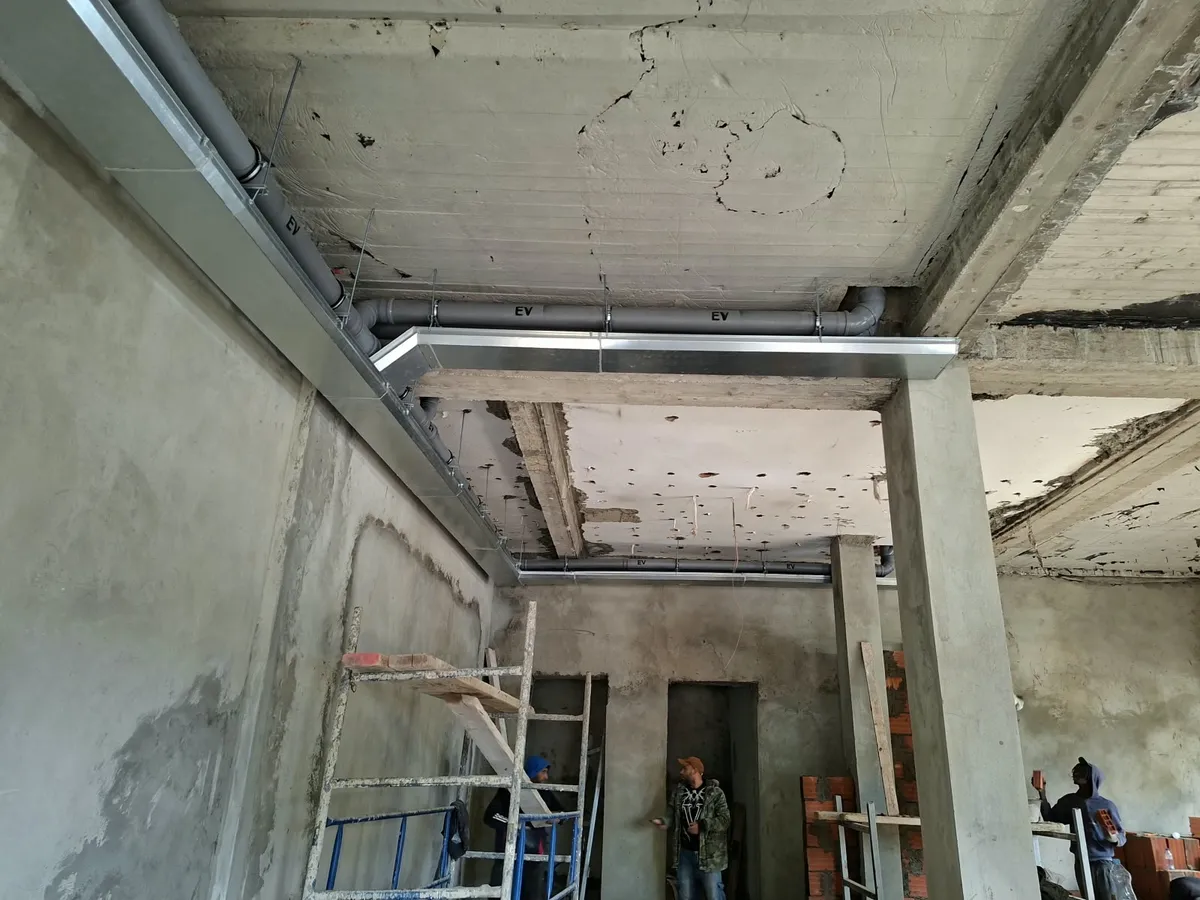 Réseaux d'évacuation et chemins de câbles suspendus sous la dalle d'un bâtiment en chantier