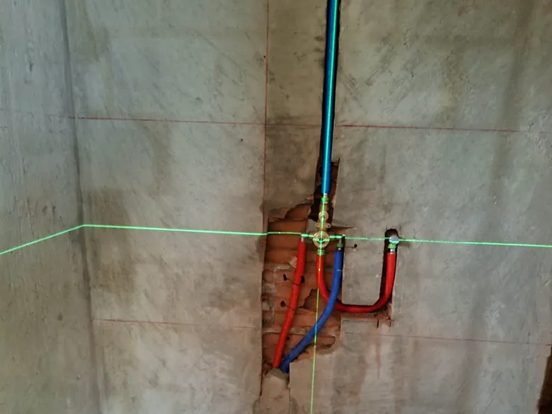 Niveau laser traçant l'emplacement des arrivées d'eau sur un mur