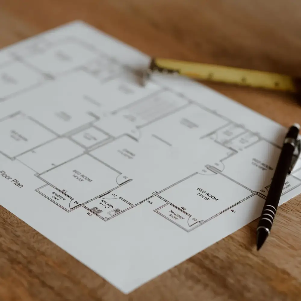 Plan d'architecte, stylo et mètre ruban posés sur une table