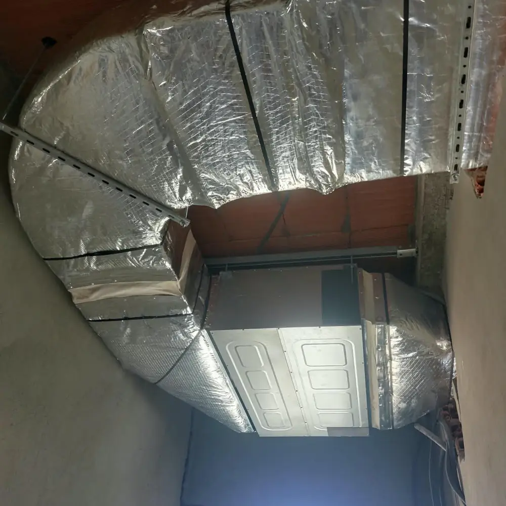 Unité de climatisation gainable raccordée à ses gaines isolées, avant la pose du faux plafond