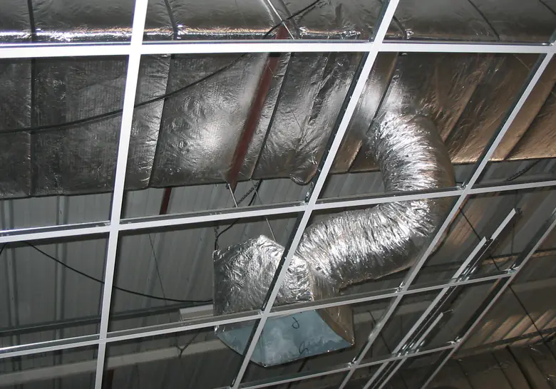 Gaine flexible isolée raccordée à un caisson de diffusion au-dessus d'un faux plafond